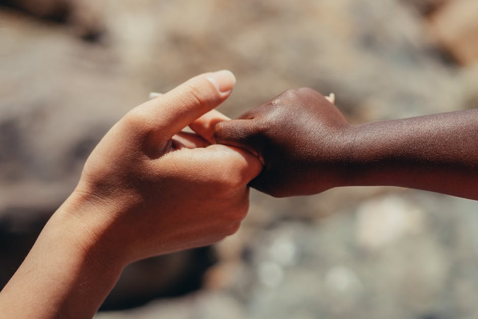 Close-up of two hands of different skin tones holding each other in support.